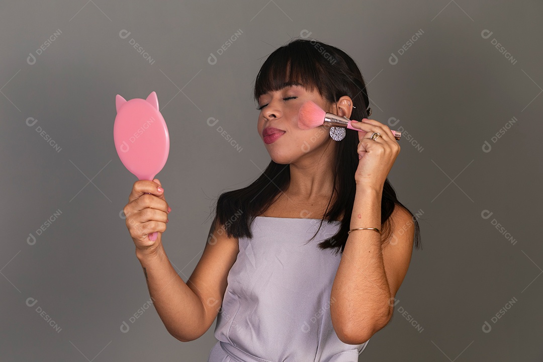 Linda mulher segurando espelho e pincel sobre fundo isolado