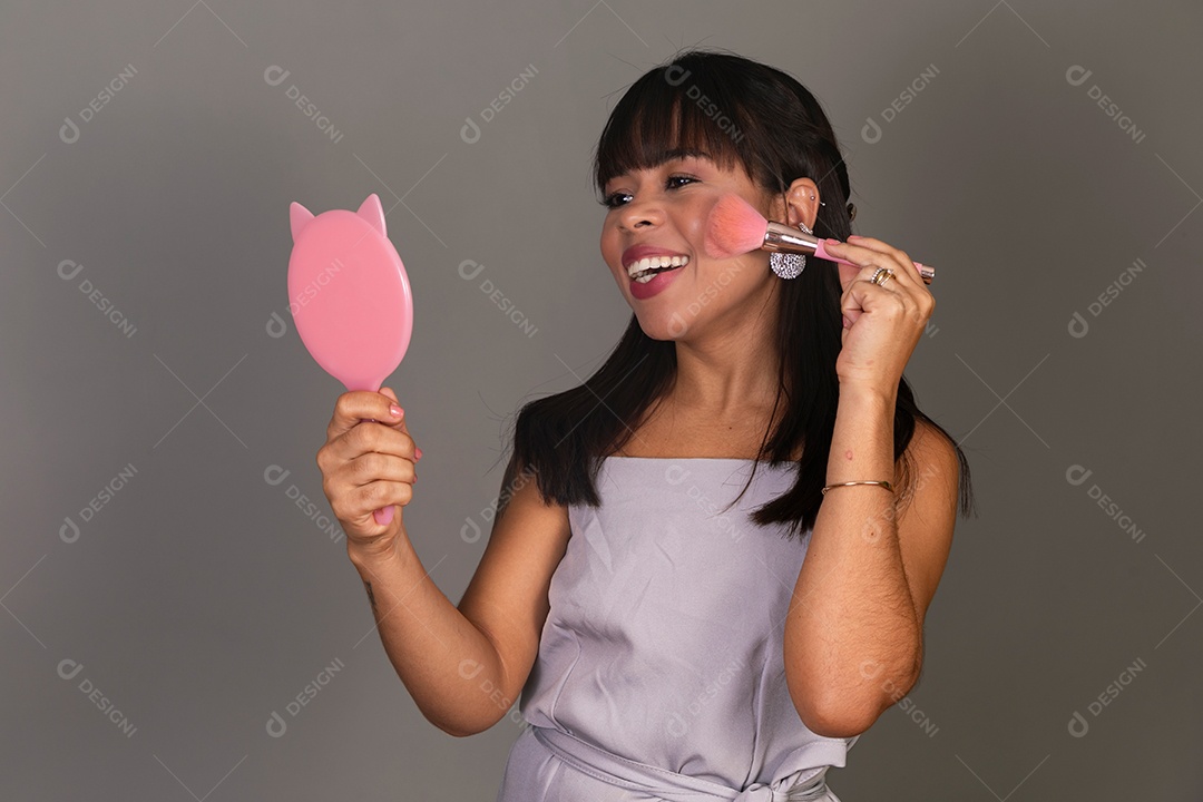 Linda mulher segurando espelho e pincel sobre fundo isolado