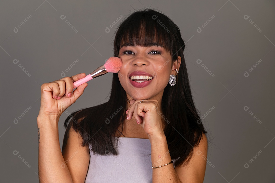 Linda mulher com blusa violeta segurando pincel sobre fundo isolado