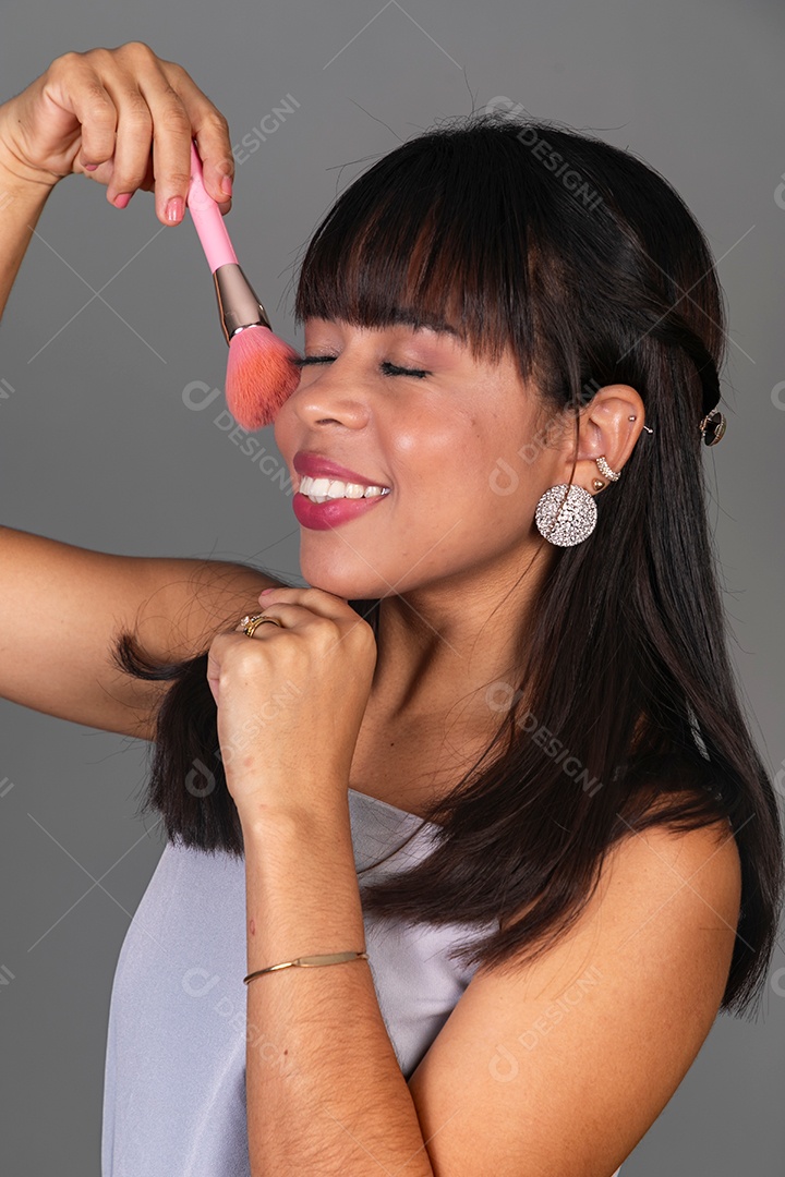 Linda mulher com blusa violeta segurando pincel sobre fundo isolado