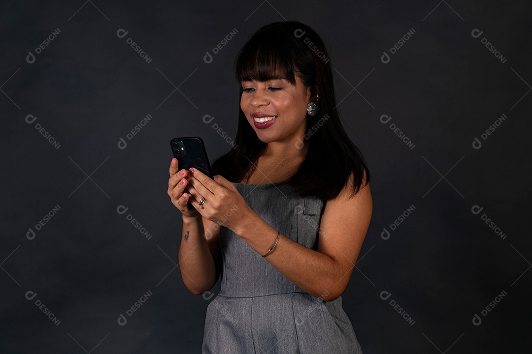 Linda mulher de roupa preta segurando smartphone sobre fundo isolado