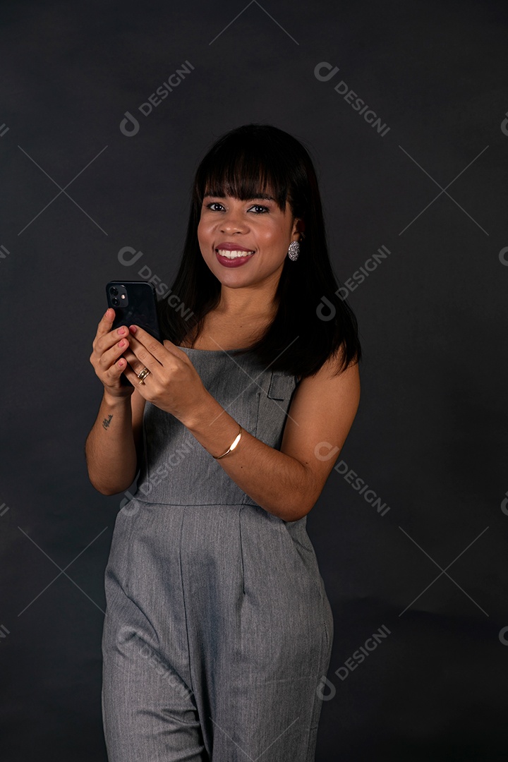 Linda mulher de roupa preta segurando smartphone sobre fundo isolado