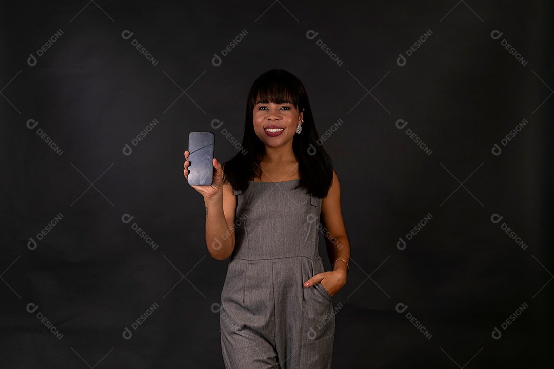 Linda mulher de roupa preta segurando smartphone sobre fundo isolado