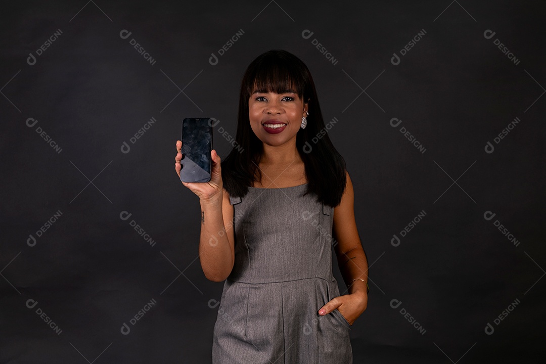 Linda mulher de roupa preta segurando smartphone sobre fundo isolado