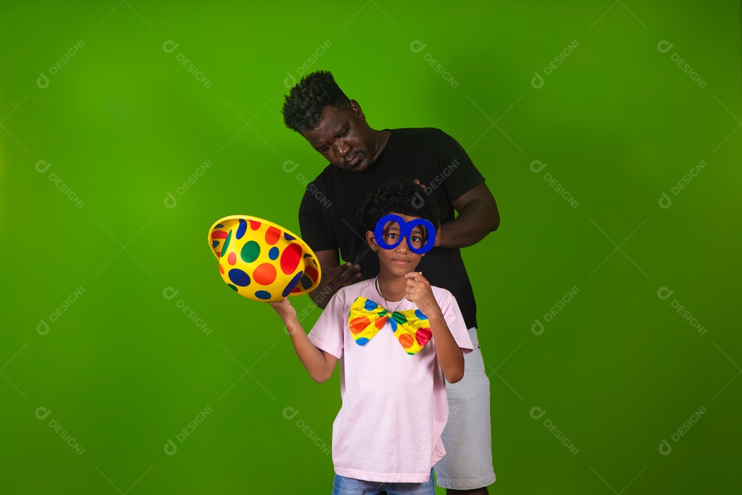 Lindo garoto fantasiado de palhaço ao lado do pai sobre fundo verde isolado