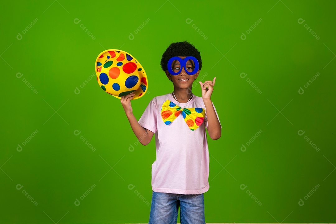 Lindo garoto fantasiado de palhaço sobre fundo verde isolado