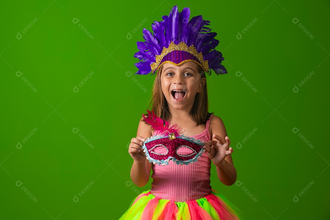 Linda garota fantasiada segurando máscara sobre fundo verde isolado