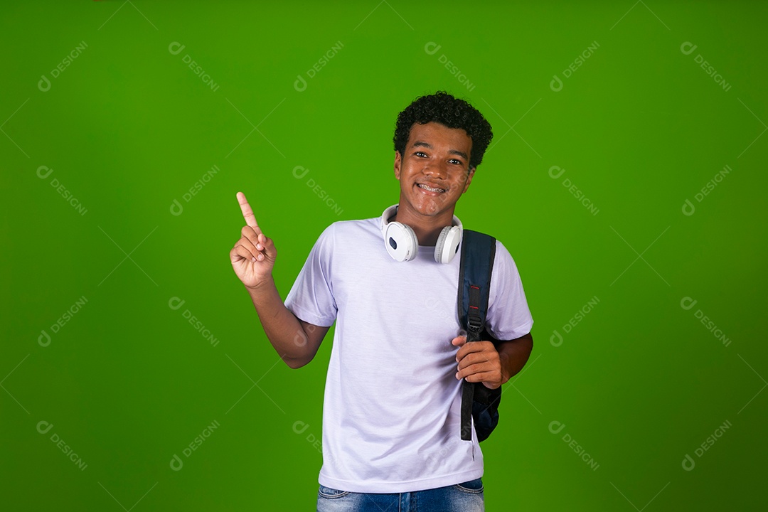 Lindo garoto negro usando fone de ouvido e mochila sobre fundo verde isolado