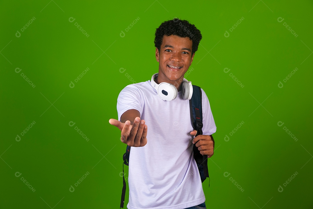 Lindo garoto negro usando fone de ouvido e mochila sobre fundo verde isolado