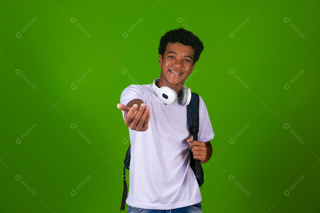 Lindo garoto negro usando fone de ouvido e mochila sobre fundo verde isolado