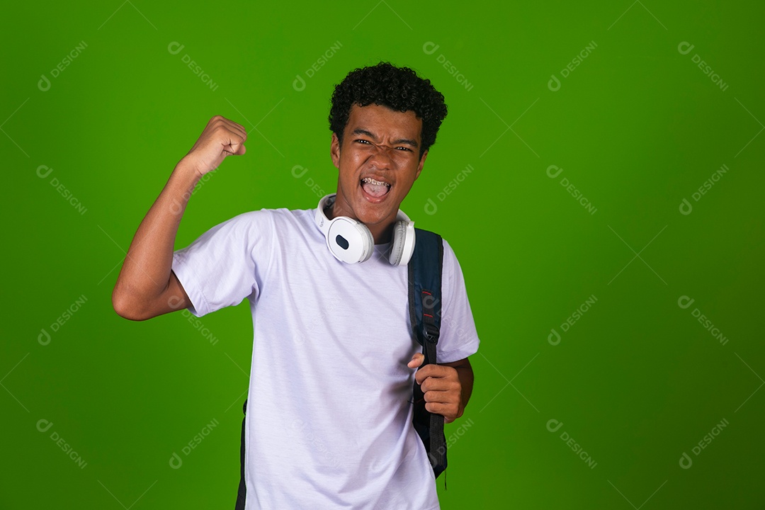 Lindo garoto negro usando fone de ouvido e mochila sobre fundo verde isolado