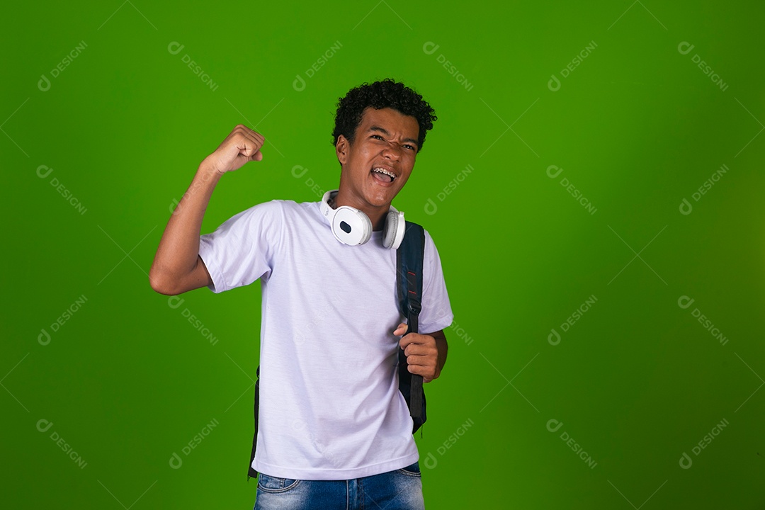 Lindo garoto negro usando fone de ouvido e mochila sobre fundo verde isolado