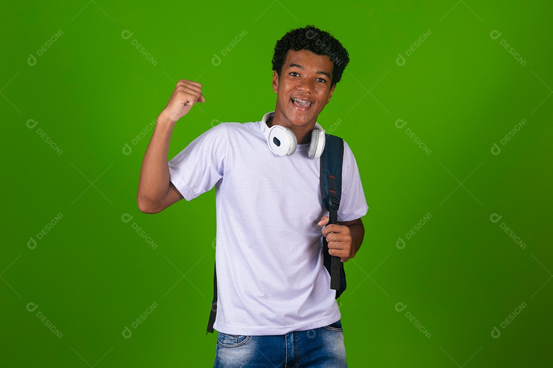 Lindo garoto negro usando fone de ouvido e mochila sobre fundo verde isolado