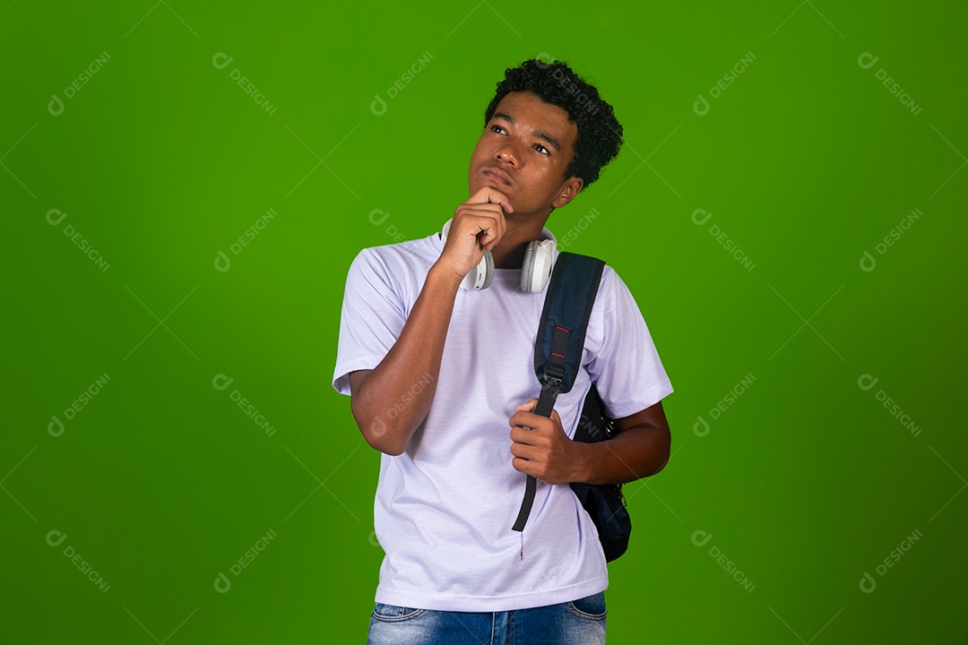 Lindo garoto negro usando fone de ouvido e mochila sobre fundo verde isolado