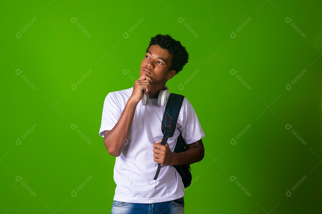 Lindo garoto negro usando fone de ouvido e mochila sobre fundo verde isolado