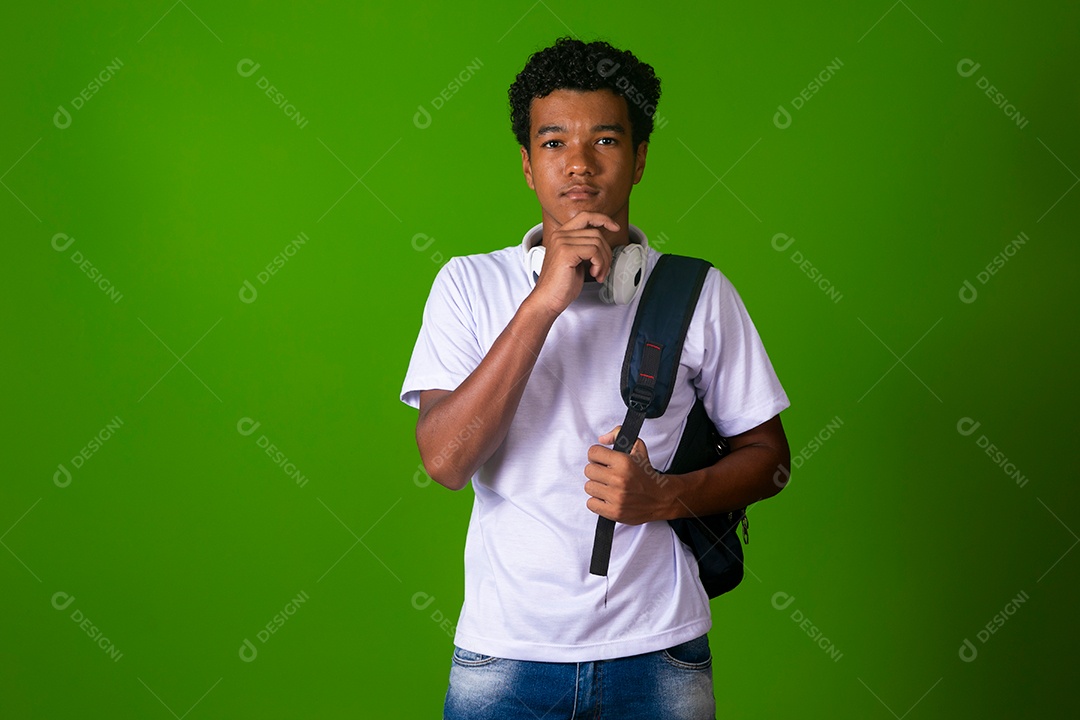 Lindo garoto negro usando fone de ouvido e mochila sobre fundo verde isolado