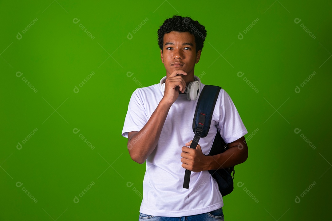 Lindo garoto negro usando fone de ouvido e mochila sobre fundo verde isolado