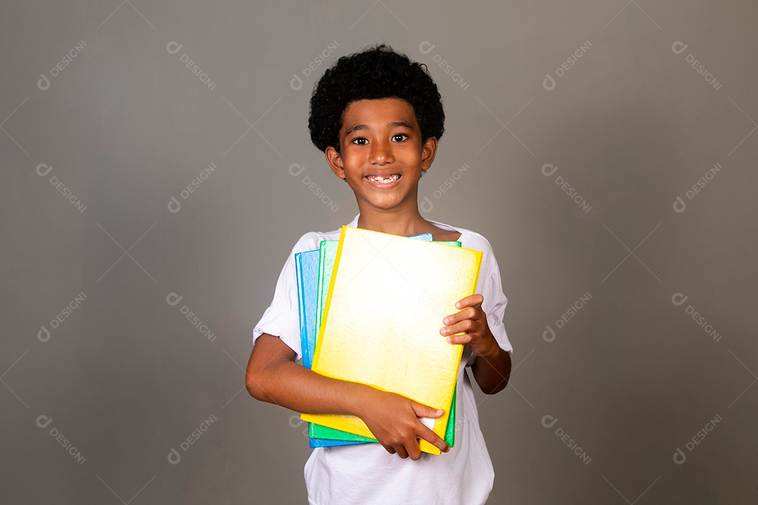 Lindo garoto negro sorridente segurando cadernos sobre fundo isolado