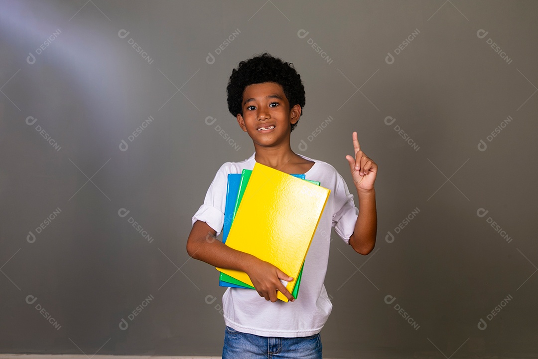 Lindo garoto negro sorridente segurando cadernos sobre fundo isolado