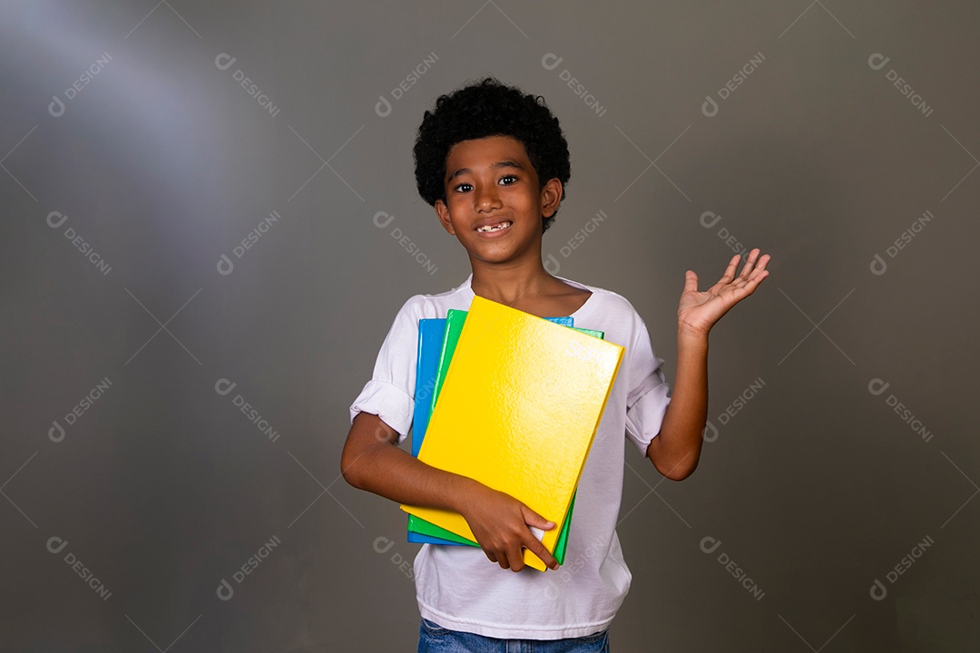 Lindo garoto negro sorridente segurando cadernos sobre fundo isolado