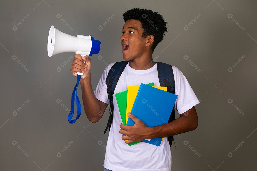 Lindo garoto negro usando bolsa e segurando cadernos e um mega fone sobre um fundo isolado