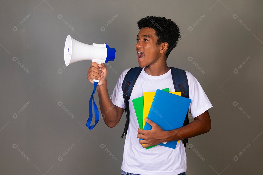 Lindo garoto negro usando bolsa e segurando cadernos e um alto falante sobre fundo isolado