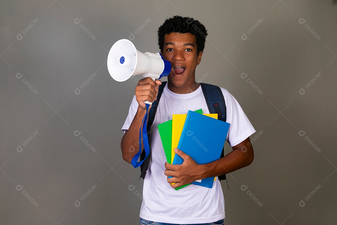 Lindo garoto negro usando bolsa e segurando cadernos e um alto falante sobre fundo isolado