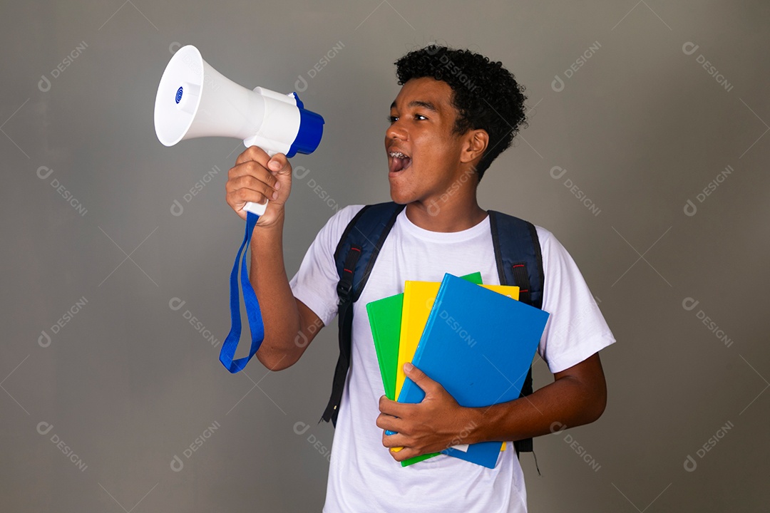 Lindo garoto negro usando bolsa e segurando cadernos e um alto falante sobre fundo isolado