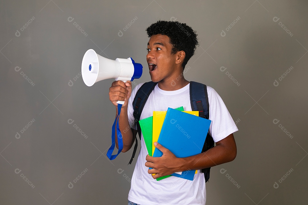 Lindo garoto negro usando bolsa e segurando cadernos e um alto falante sobre fundo isolado