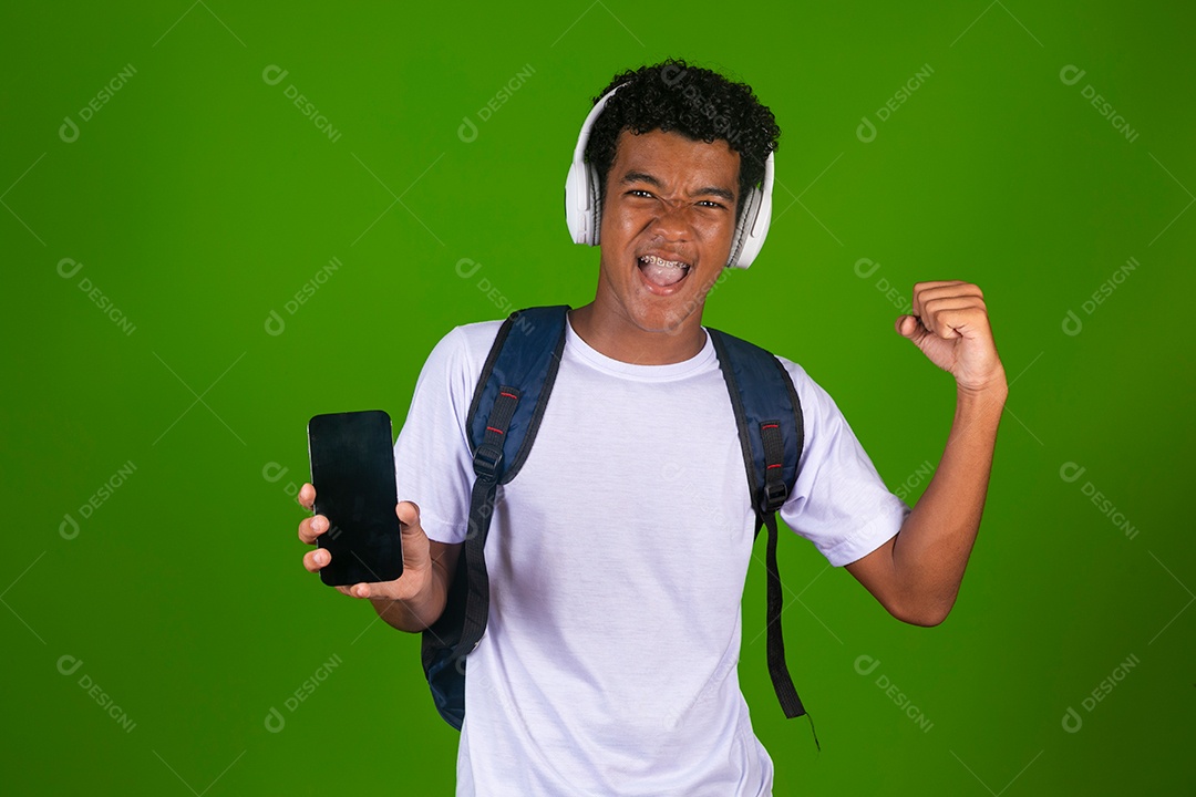 Lindo garoto negro usando bolsa e fone de ouvido segurando smartfhone sobre fundo isolado