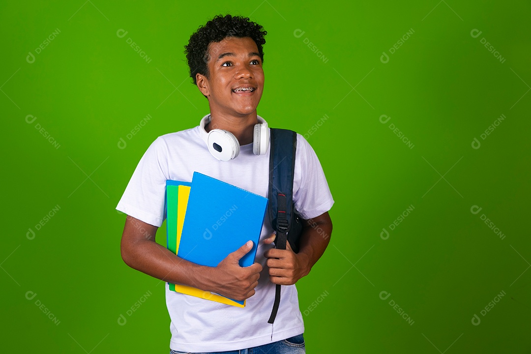 Lindo garoto negro usando bolsa e fone de ouvido segurando caderno sobre fundo isolado
