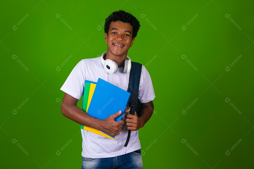 Lindo garoto negro usando bolsa e fone de ouvido segurando caderno sobre fundo isolado