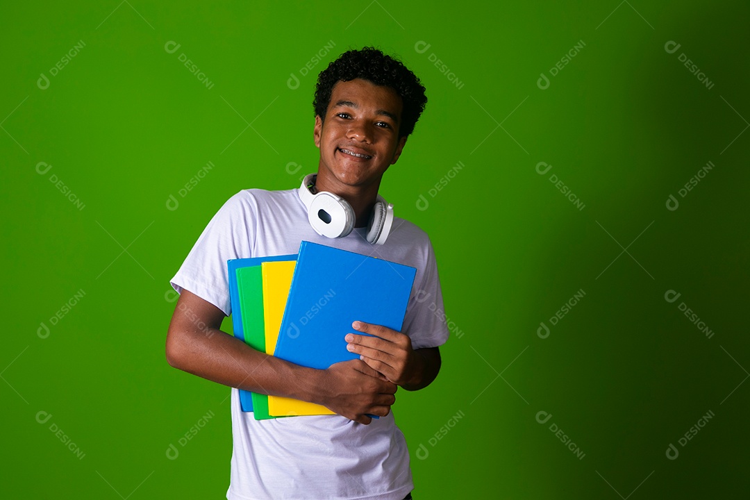 Lindo garoto negro usando bolsa e fone de ouvido segurando caderno sobre fundo isolado