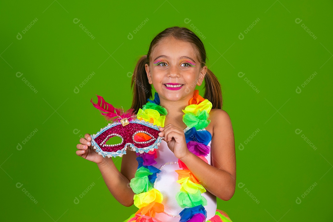 Linda garotinha loira fantasiada para carnaval segurando mascara sobre fundo verde isolado