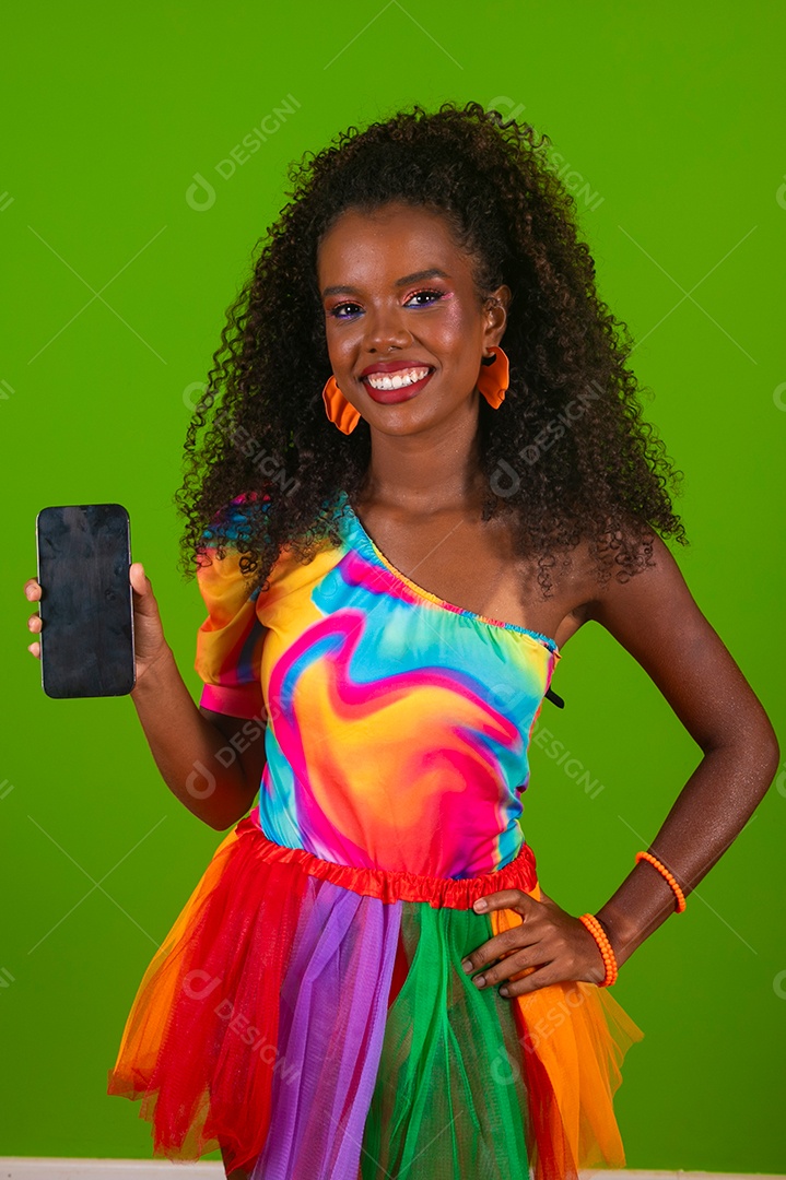 Linda morena sorridente com roupas colorida segurando smartfhone sobre fundo verde isolado