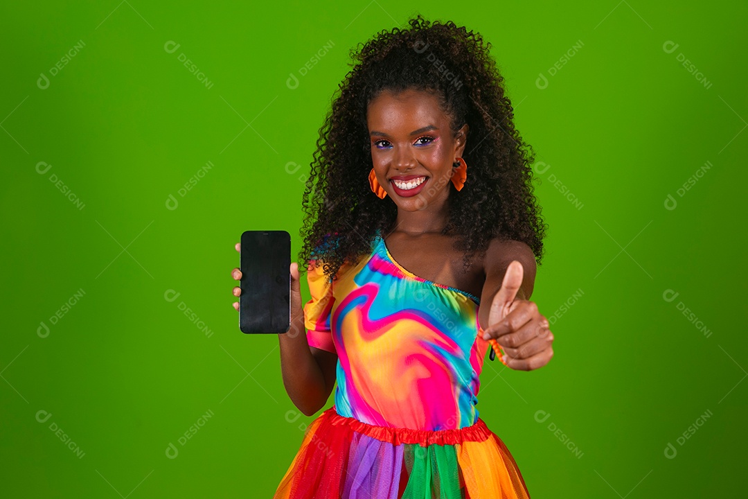 Linda morena sorridente com roupas colorida segurando smartfhone sobre fundo verde isolado