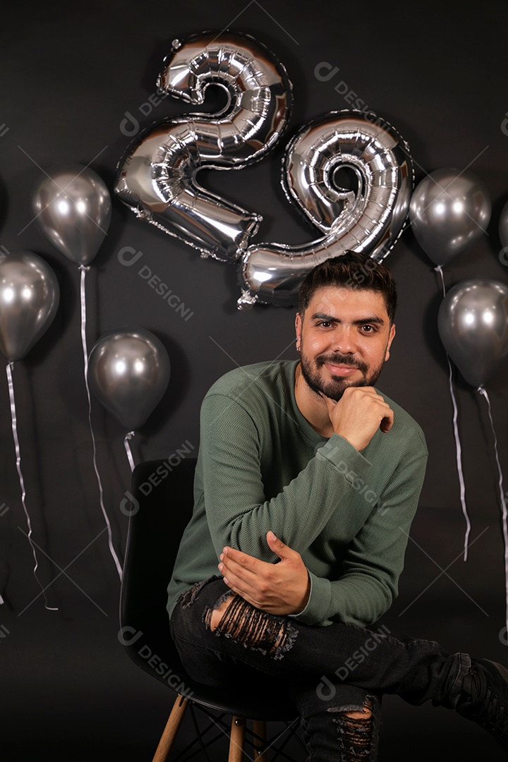 Lindo homem sorridente fazendo aniversário sobre fundo com balões isolado