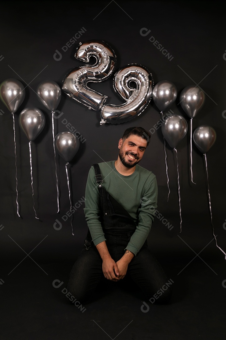 Lindo homem sorridente fazendo aniversário sobre fundo com balões isolado