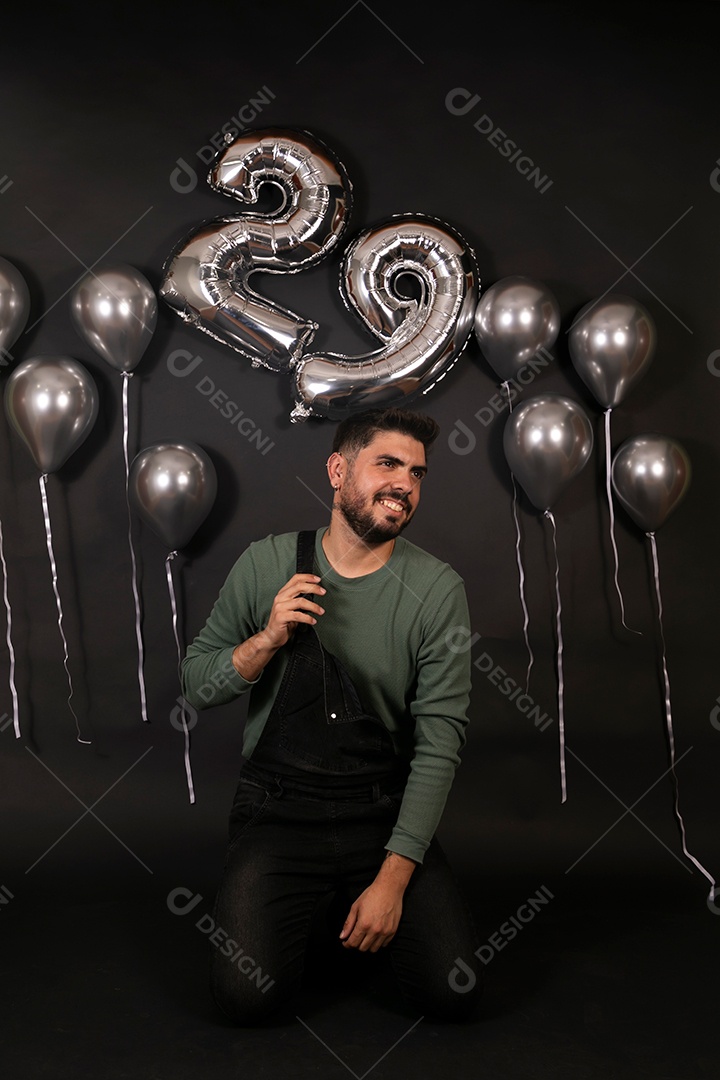 Lindo homem sorridente fazendo aniversário sobre fundo com balões isolado