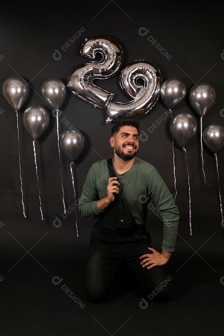 Lindo homem sorridente fazendo aniversário sobre fundo com balões isolado