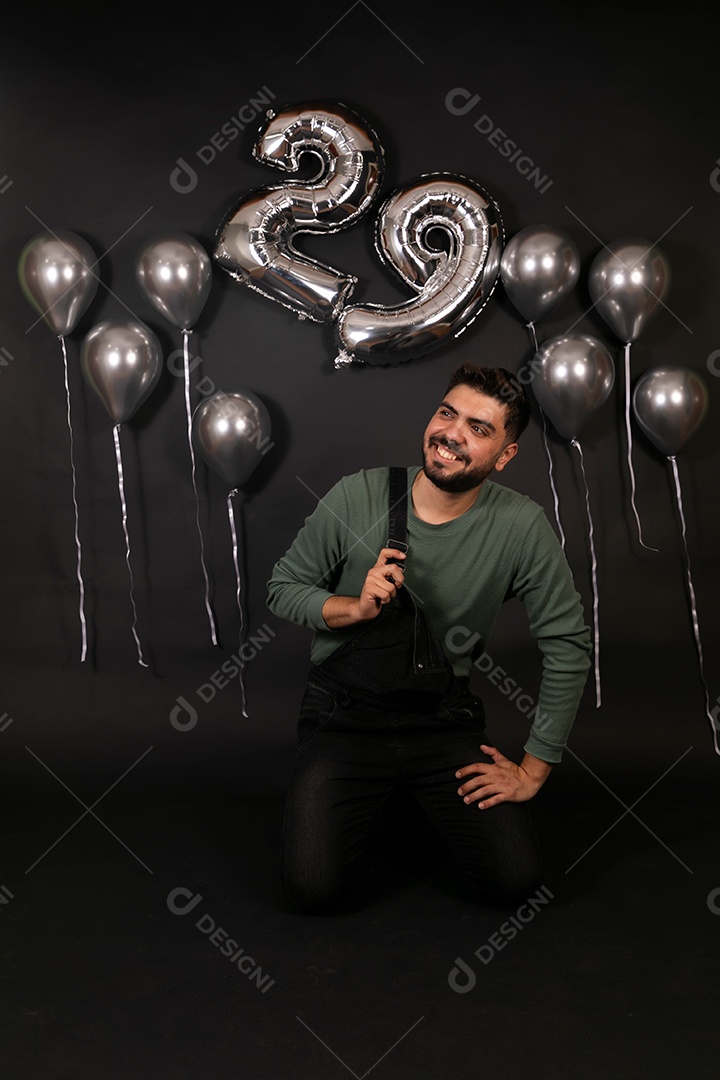 Lindo homem sorridente fazendo aniversário sobre fundo com balões isolado