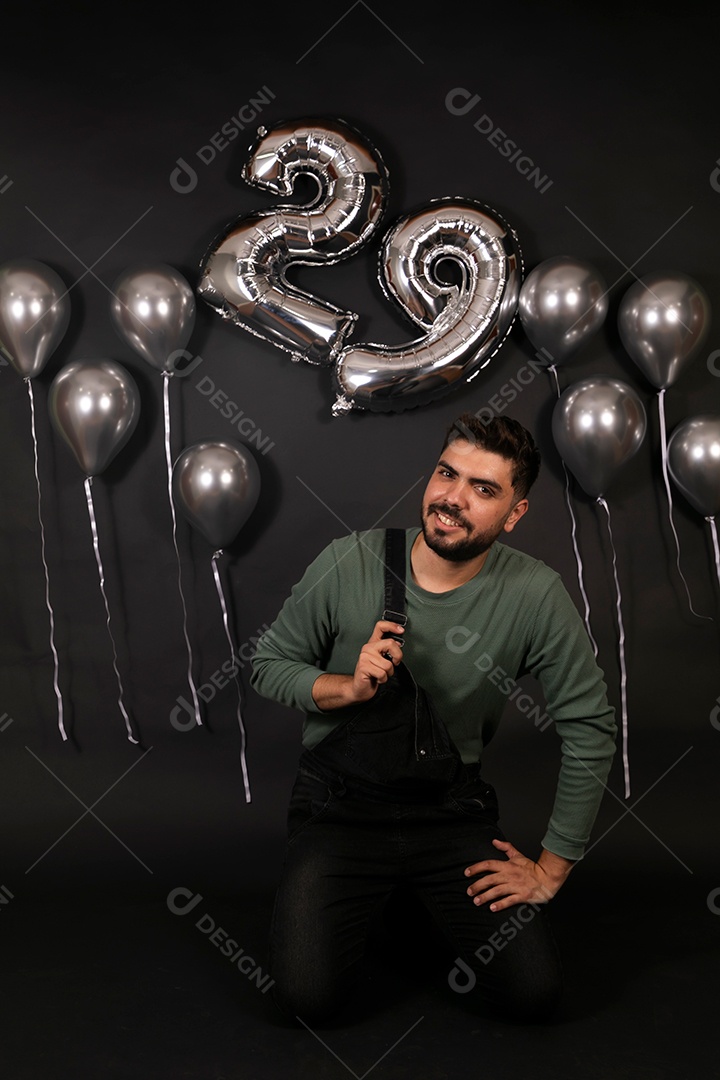 Lindo homem sorridente fazendo aniversário sobre fundo com balões isolado
