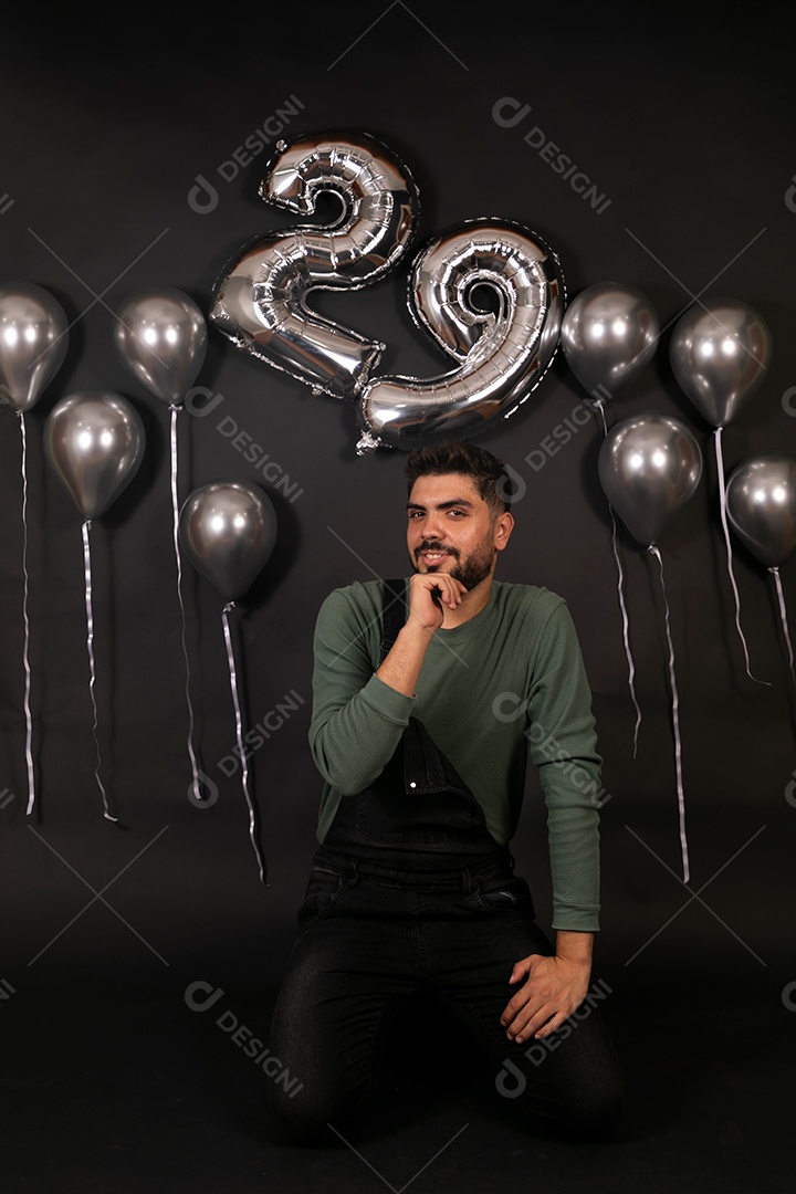Lindo homem sorridente fazendo aniversário sobre fundo com balões isolado