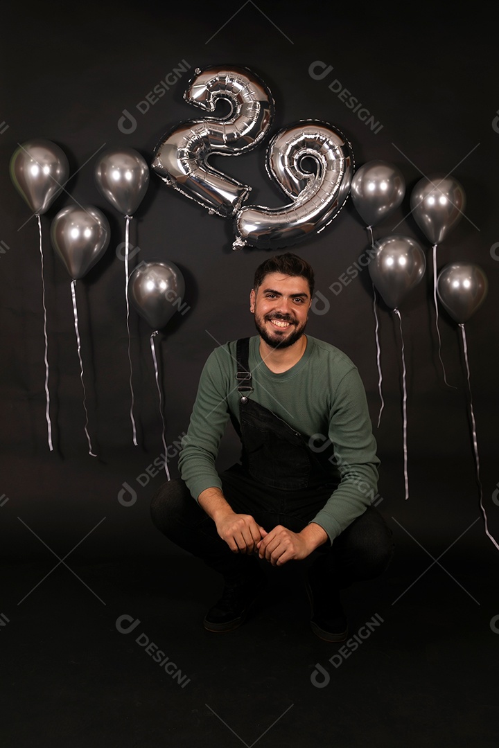 Lindo homem sorridente fazendo aniversário sobre fundo com balões isolado