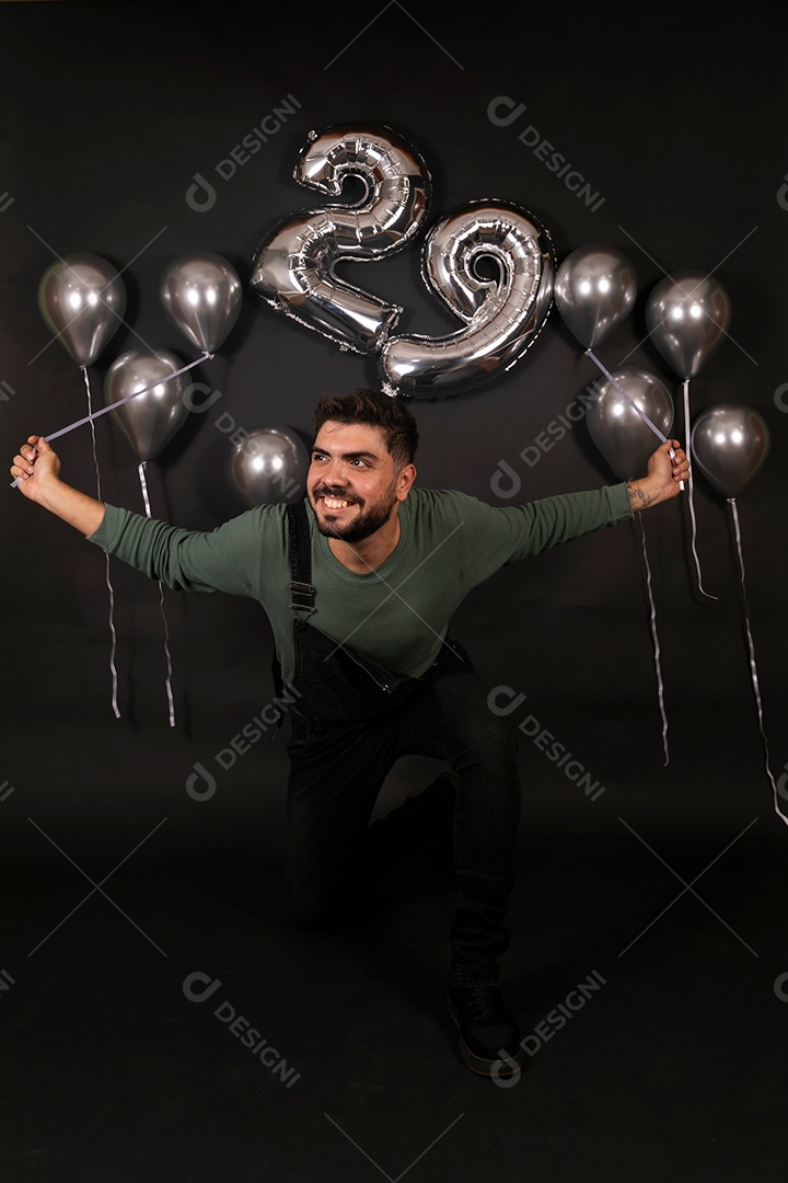 Lindo homem sorridente fazendo aniversário sobre fundo com balões isolado