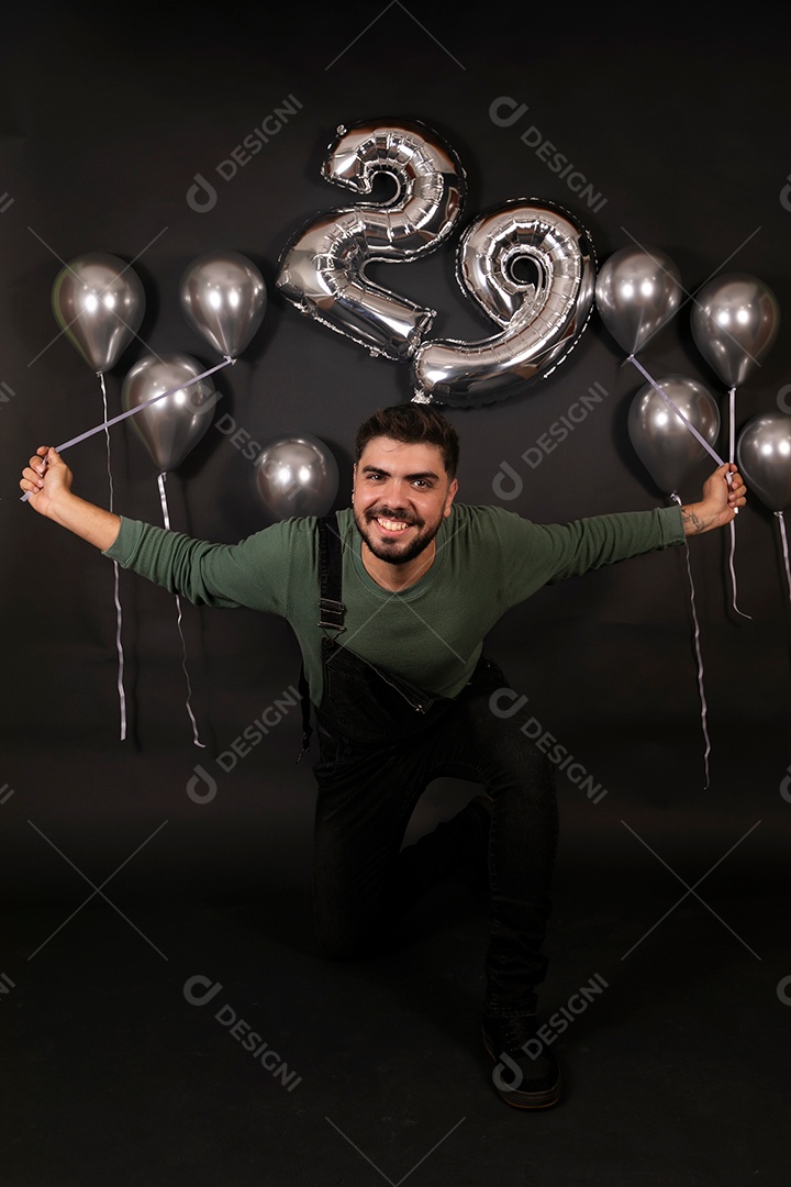 Lindo homem sorridente fazendo aniversário sobre fundo com balões isolado