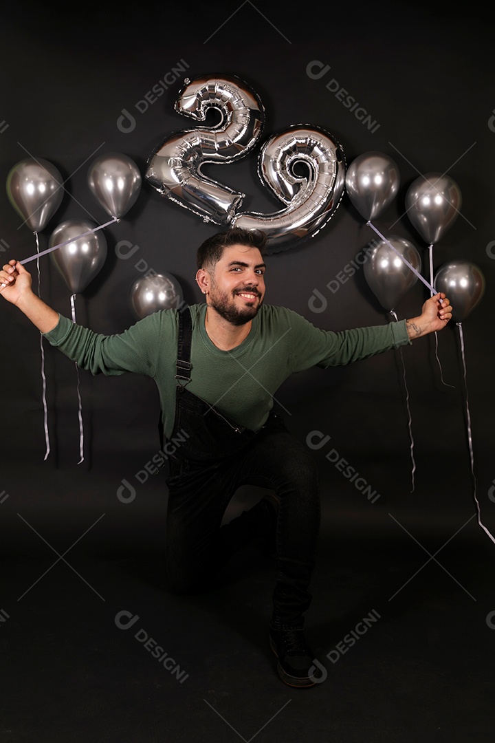 Lindo homem sorridente fazendo aniversário sobre fundo com balões isolado