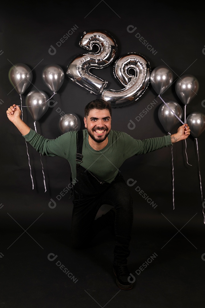 Lindo homem sorridente fazendo aniversário sobre fundo com balões isolado