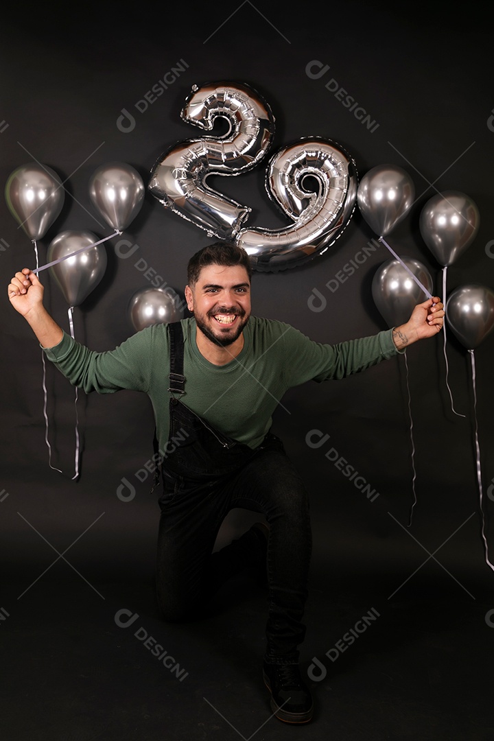 Lindo homem sorridente fazendo aniversário sobre fundo com balões isolado