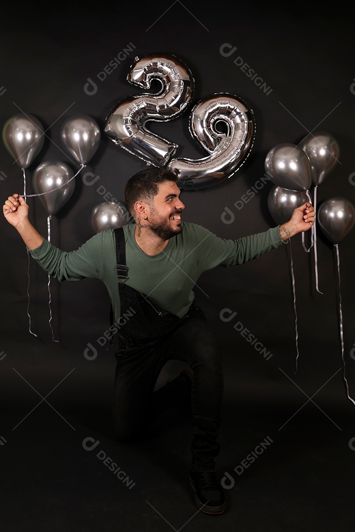 Lindo homem sorridente fazendo aniversário sobre fundo com balões isolado